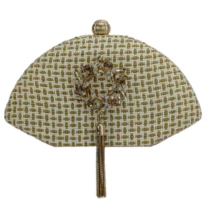 Detailed view of a semi-circular woven straw evening clutch bag with rhinestone wreath and tassel.