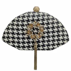 Black and white houndstooth woven straw clutch bag with golden rhinestone wreath and tassel.