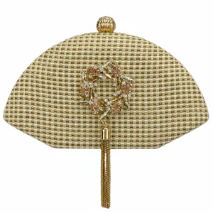 Close-up detail of the woven straw evening clutch bag featuring rhinestone flower and metal tassel.