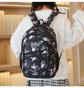 Detailed view of cute black cartoon bunny print school backpack worn by model in room setting.
