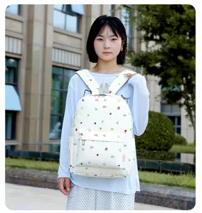 Vue détaillée d'un joli sac à dos d'école floral blanc porté par un mannequin en extérieur.