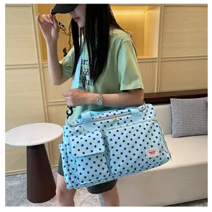 Vue détaillée du sac de voyage bleu clair à pois, avec poche avant et poignées pratiques.