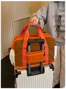 Grande borsone da viaggio con fascia per valigia e design a blocchi di colore.