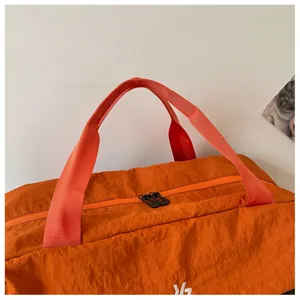 Vista dettagliata del borsone da viaggio arancione in nylon resistente con robuste cerniere.