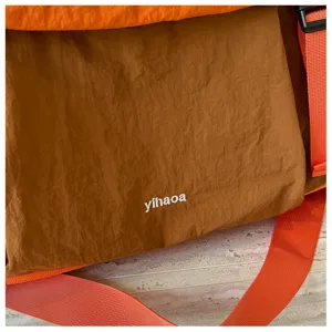 Primo piano della texture del tessuto della borsa fitness espandibile e cinturino arancione.