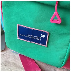 Groene reistas close-up detail met duurzame stof, roze banden en een geborduurde patch.