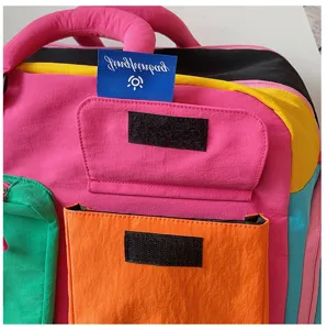 Detailopname van de kleurrijke nylon reistas met handige voorzak en merketiket.