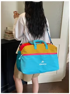 Dettaglio della borsa da viaggio colorata con tracolla, manici e grande capienza interna.