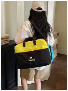 Primo piano della borsa da viaggio colorata indossata dal modello, con doppi manici e design.