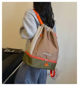 Detailansicht des braunen karierten Kordelzugrucksacks mit gruenem Boden und oranger Kordel.
