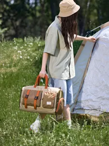 Kakikleurige reistas met oranje banden en ruitzakken, getoond buiten bij een tent.