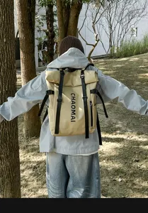 Outdoor scene detail view showing the khaki roll-top backpack with black straps worn.
