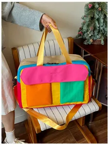 Detail shot of color-blocked travel duffel bag showcasing multiple pockets and sturdy handles.
