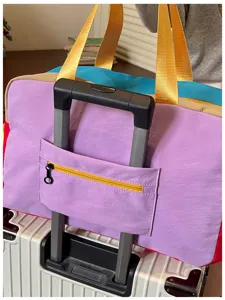 Colorblock travel duffel bag with trolley sleeve and top handles for luggage and gym use.