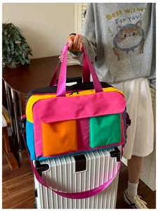 Color-blocked travel duffel bag detail showing vibrant pink, yellow, blue, and orange panels.
