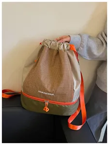 Detailansicht des Karo-Kordelzugs-Rucksacks mit auffälligen Kontrastriemen und unterem Reißverschlussfach.