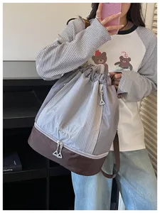 Detailansicht des grauen Kordelzug-Rucksacks mit braunem Boden und Sportfach.