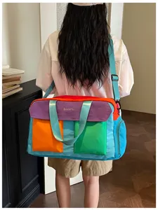 Detail view of the colorful color-blocked travel bag worn on shoulder for short trips.
