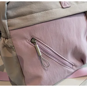 Close-up detail of a women's travel duffel bag showing zipper pocket and fabric texture.