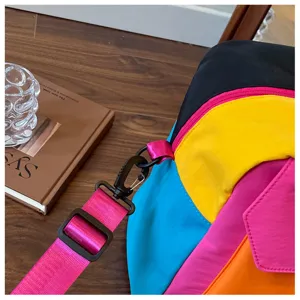 Color-block travel duffel bag detail, vibrant pink strap and multi-color nylon fabric.