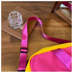 Close-up detail view of vibrant pink yellow colorblocked travel duffel bag strap and fabric.