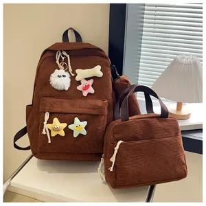 Vista dettagliata dello zaino in corduroy marrone e del set borsa pranzo con simpatici decori in peluche.