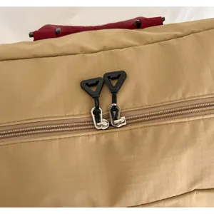 Detailed view of travel duffel bag zipper and red handle, durable mesh fabric.