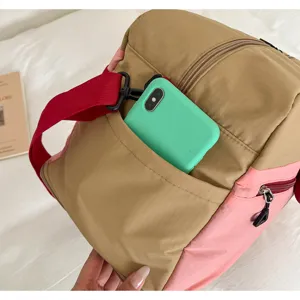 Color-block travel duffle bag detail showcasing front phone pocket and durable canvas material.