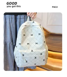 Gros plan du sac à dos en velours côtelé blanc avec des motifs de nœuds noirs et surpiqûres.