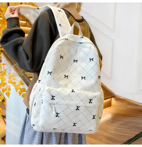 Vue détaillée du sac à dos en velours côtelé blanc avec broderie nœud noir et losanges.