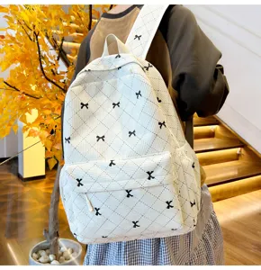 Sac à dos en velours côtelé blanc avec broderie de nœuds noirs, matelassé et poche avant détaillée.