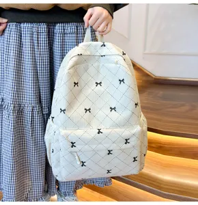 Vue détaillée du sac à dos en velours côtelé blanc avec motif de nœuds noirs et poches.