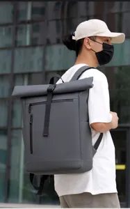 Detail view of grey waterproof roll-top backpack worn by model outdoors for commuting.