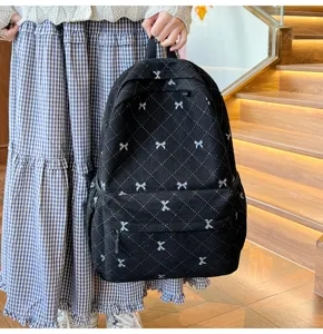 Détail de sac à dos en velours côtelé noir avec motif nœud et matelassage losanges.