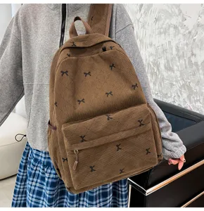 Vue détaillée du sac à dos en velours côtelé marron avec motifs de nœuds, cartable d'école.