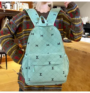 Vue de détail du sac à dos en velours côtelé vert clair avec de jolies broderies de nœuds.