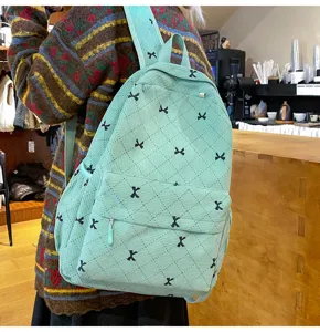 Vue détaillée d'un sac à dos en velours côtelé vert menthe avec motif de nœuds noirs.