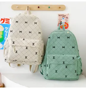 Vue de détail du sac à dos scolaire en velours côtelé avec joli motif de nœuds et poche avant.
