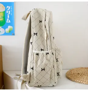 Vue latérale détaillée du sac à dos en velours côtelé beige avec motifs de nœuds mignons.
