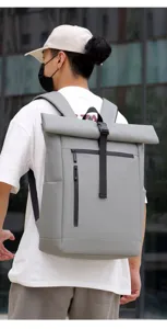 Detail view of grey roll-top waterproof backpack with front zipper pocket and secure buckle.