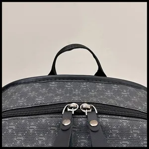 Detalle de mochila mostrando asa superior, ribete de cuero negro y doble cremallera metálica.