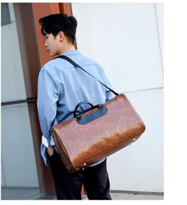 Detailansicht der braunen Reisetasche aus PU-Leder mit Kroko-Muster am Model im Freien