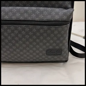 Primer plano de la mochila gris oscura con patron geometrico y bolsillo frontal con cremallera.