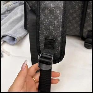 Detalle de correa de mochila con cincha resistente, hebilla ajustable y monograma.