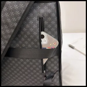 Primer plano del detalle de la mochila gris oscuro con monograma, bolsillo y teléfono.
