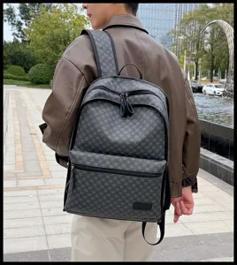 Vista detallada de una mochila gris con monograma al aire libre, con lona resistente y cremalleras.