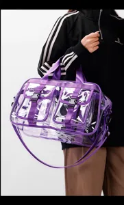 Transparente PVC Reisetasche mit lila Besatz und mehreren Vortaschen, Detailansicht des Schultergurts.