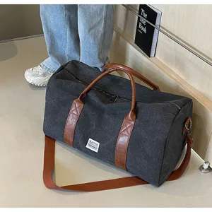 Detailopname van donkergrijze canvas reistas met bruine lederen handgrepen en schouderriem.
