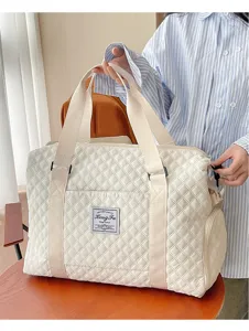 Detailansicht der weißen gesteppten Reisetasche mit strukturierter Oberfläche und Trageriemen.