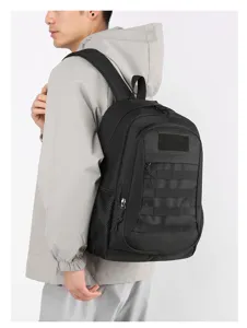 Detail view of black tactical backpack with MOLLE webbing and mesh side pocket on model.